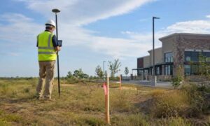 Land surveyor using GPS equipment to mark property boundaries for an ALTA and boundary survey on a Louisiana commercial property site