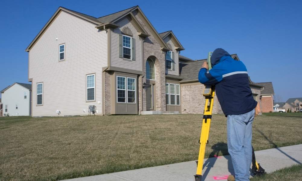 Land surveyor conducting measurements at a residential property for a land survey project